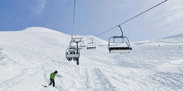 A snowy trail atop a mountain with cable cars in Albania.